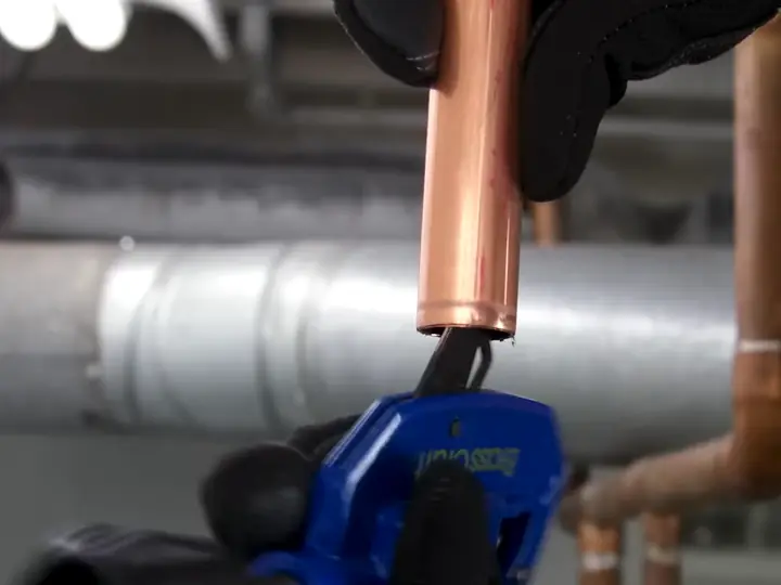 Technician cutting copper pipe for commercial water heater repair in Revere, MA