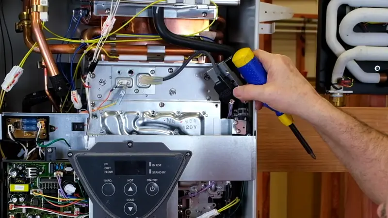 Water heater technician diagnosing a tankless unit with the front cover removed